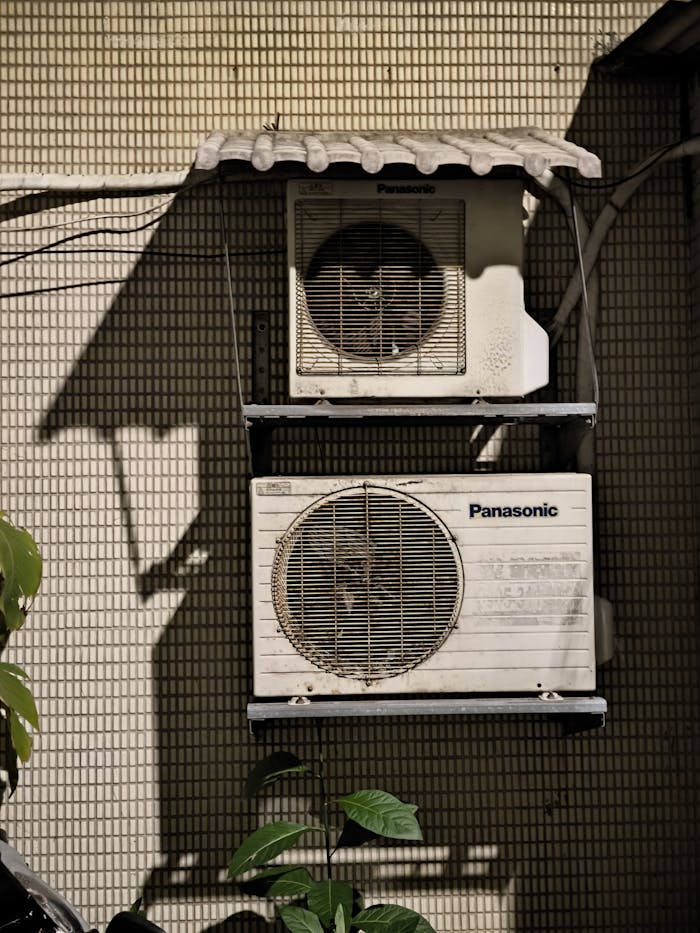 Close-up of two air conditioning units on a building facade in sunlight.