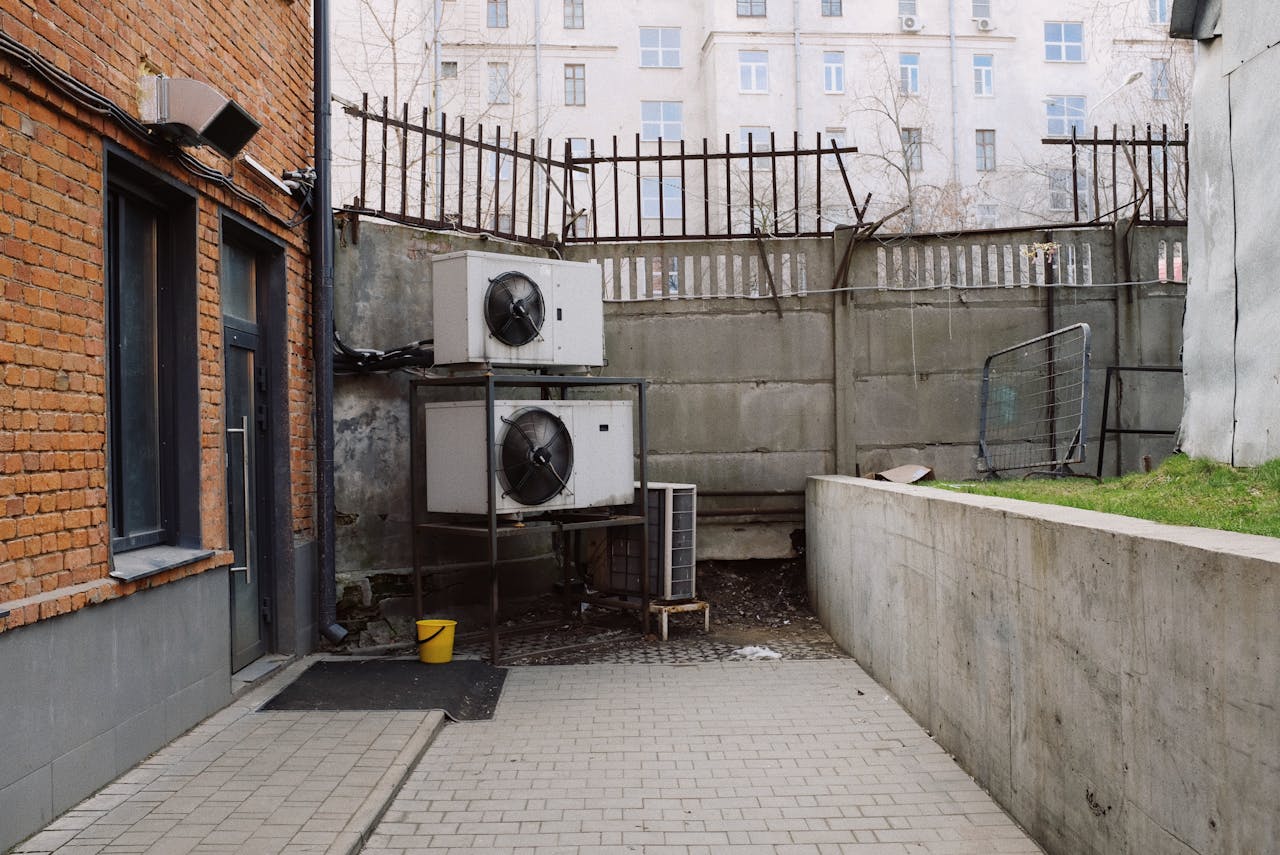 who-we-are Photo of an urban industrial setting with brick walls and air conditioning units outdoors.