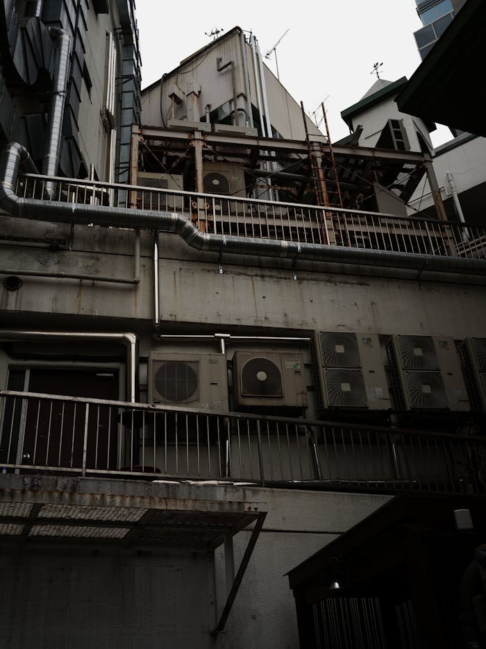 about-img Low angle view of HVAC units on a building wall in Shibuya City, showcasing urban architecture.